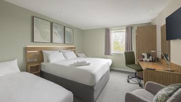 Ein Hotelzimmer mit zwei Betten, einem Schreibtisch mit Stuhl, einem Fernseher und einem Fenster mit Vorhängen.