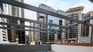 Une piscine sur le toit, dotée d’un jacuzzi, entourée d’une structure métallique et offrant une vue sur le paysage urbain.
