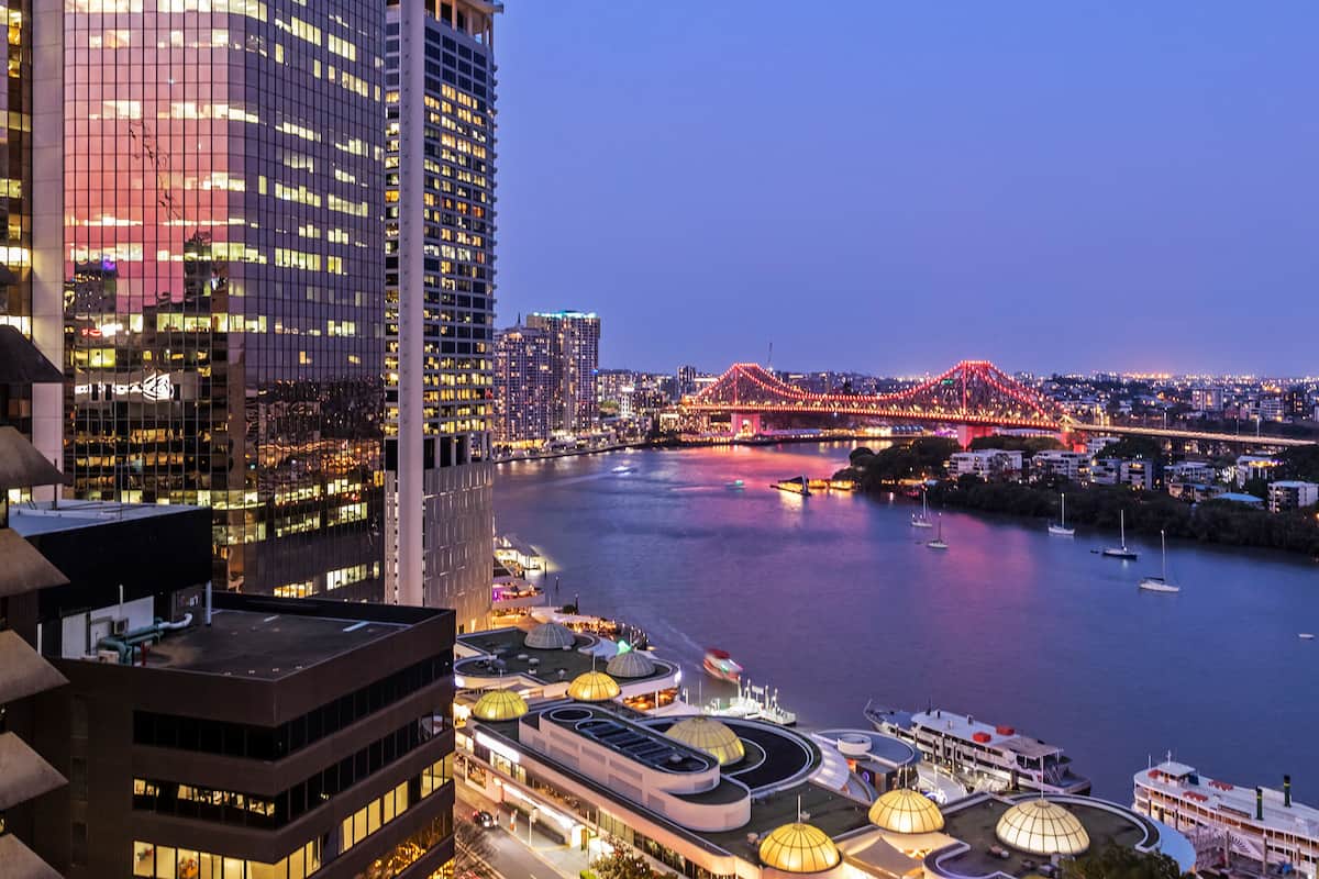 Ein Hochhaus mit moderner Architektur, Blick auf das Wasser und eine Brücke im Hintergrund.
