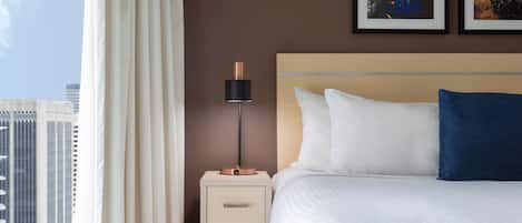 Een hotelkamer met een bed, een nachtkastje, een lamp en twee foto's in lijsten aan de muur.