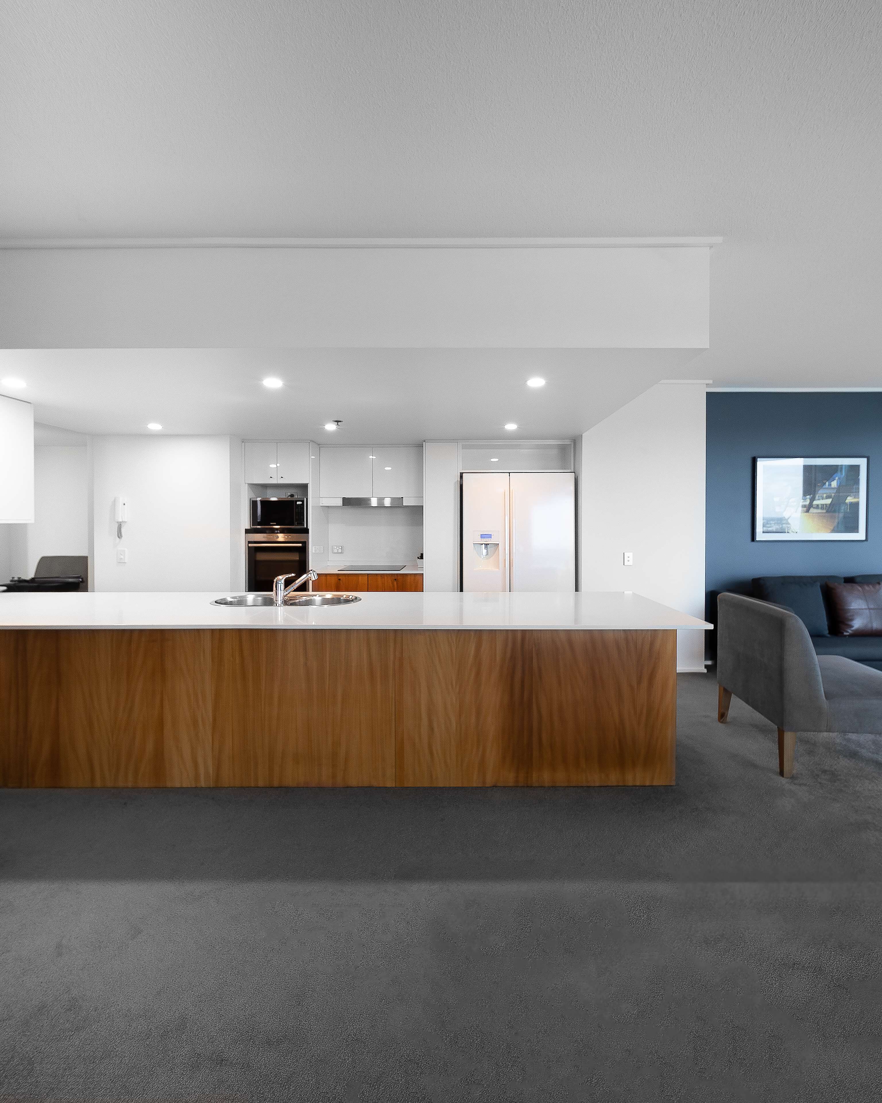 Una cocina moderna con armarios blancos, un refrigerador de acero inoxidable y una encimera de madera.