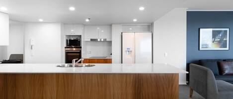 Una cocina moderna con armarios blancos, un refrigerador de acero inoxidable y una encimera de madera.