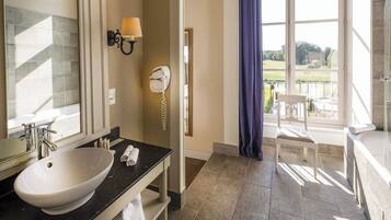 Une salle de bain avec un grand lavabo, un miroir, un porte-serviettes, un téléphone et une vue sur un court de tennis.