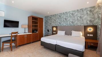 A hotel room with a bed, a desk, a chair, a wardrobe, and a television.