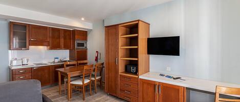 A compact kitchen with wooden cabinets, a microwave, and a dining area with a table and chairs.