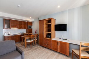 Una cocina compacta con armarios de madera, un microondas y un comedor con mesa y sillas.