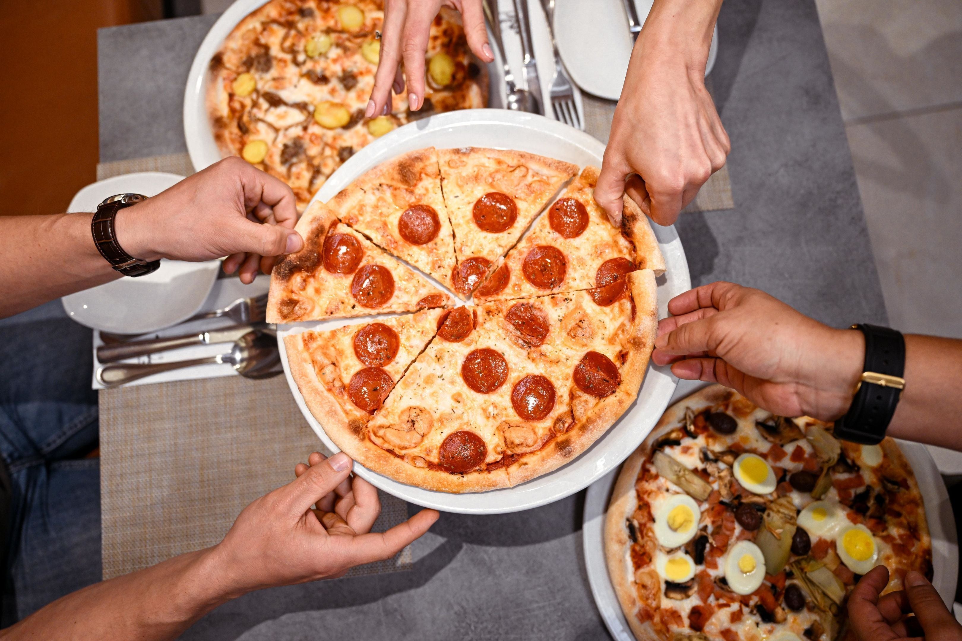 A pizza being shared among several people.
