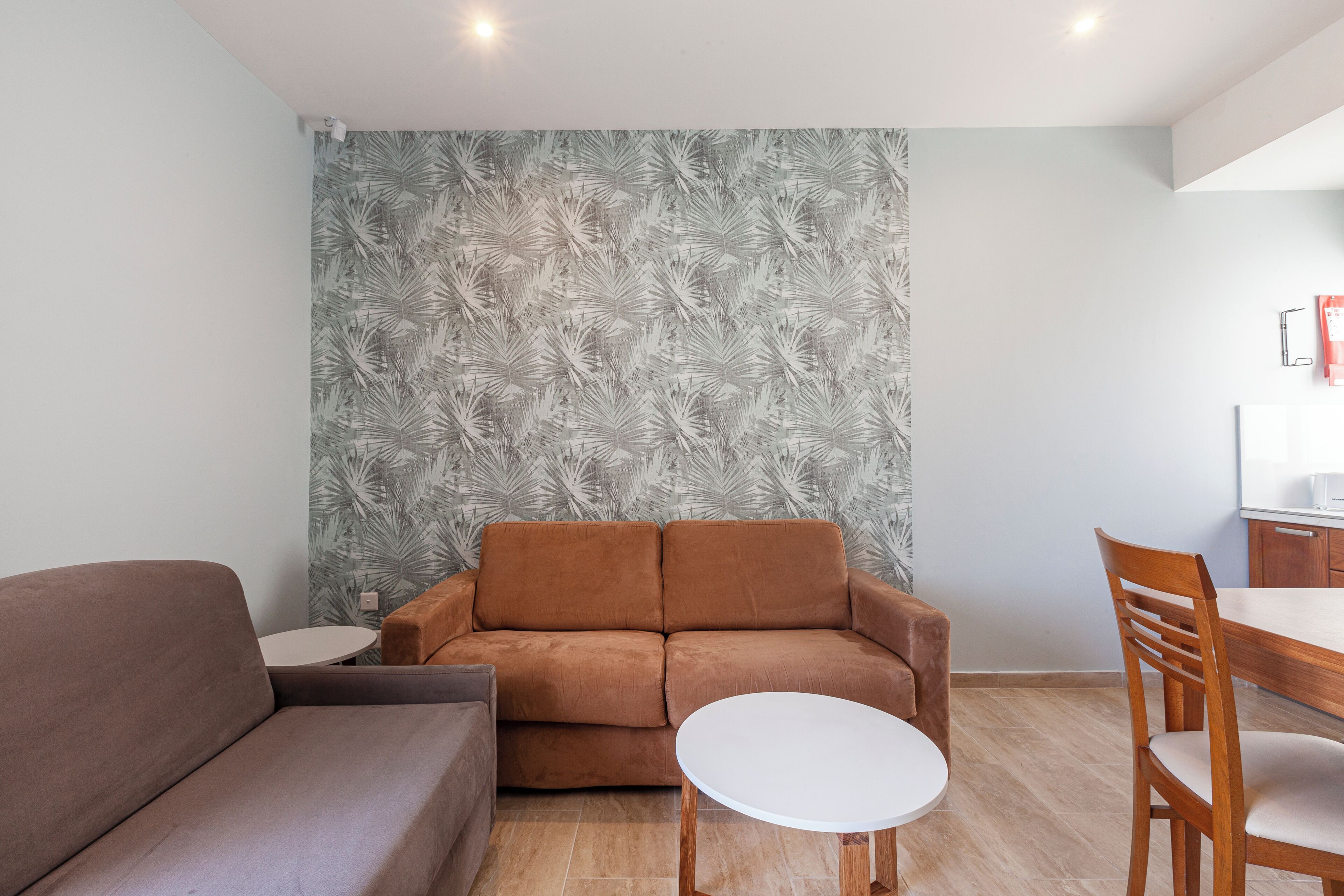 Una sala de estar moderna con un sofá marrón, una mesa redonda blanca y una silla de comedor de madera.