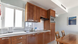 Una cocina moderna con armarios de madera, un lavamanos de acero inoxidable y un microondas empotrado.