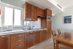 Una cocina moderna con armarios de madera, un lavamanos de acero inoxidable y un microondas empotrado.