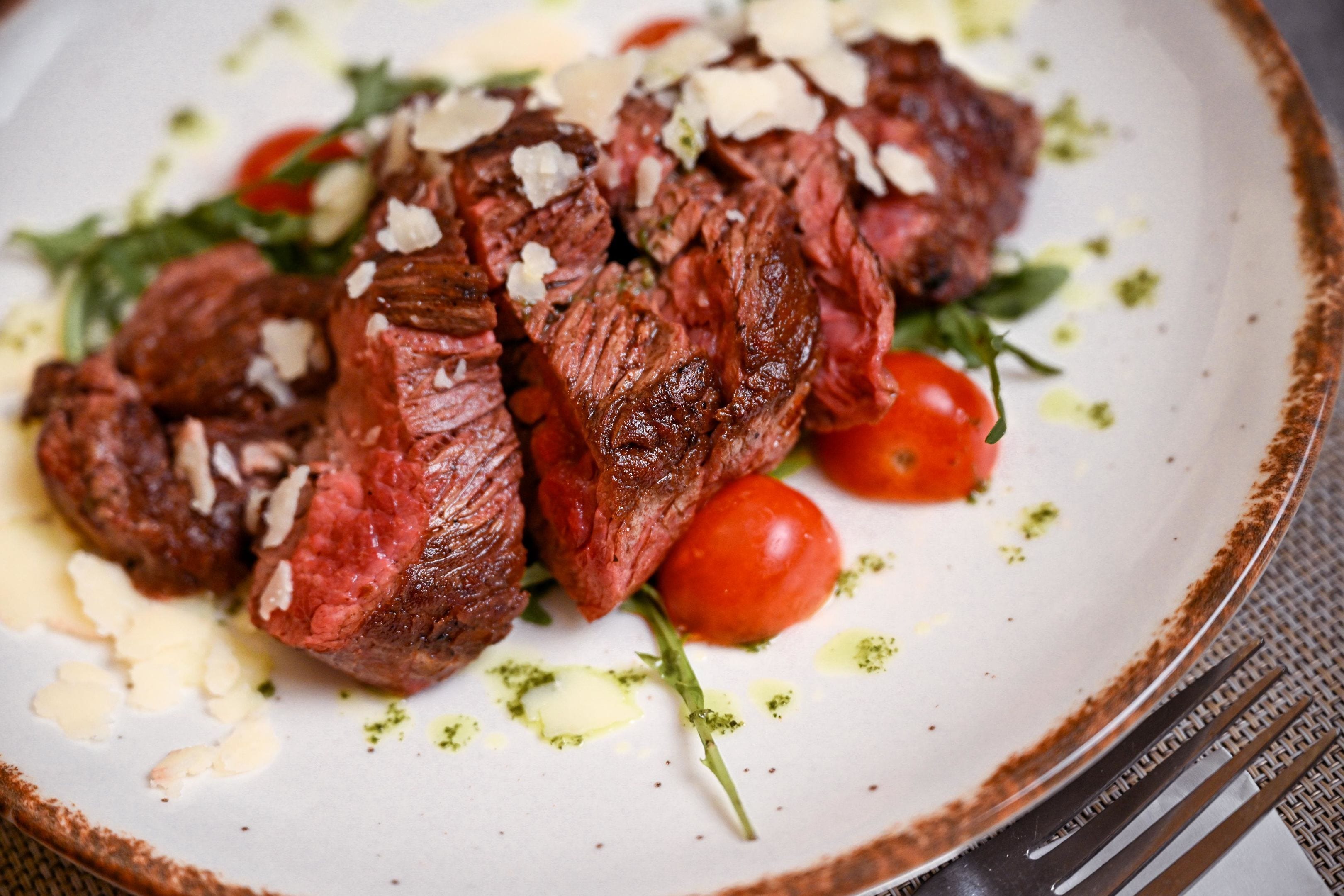 Un plato de carne con tomates cherry y una guarnición.