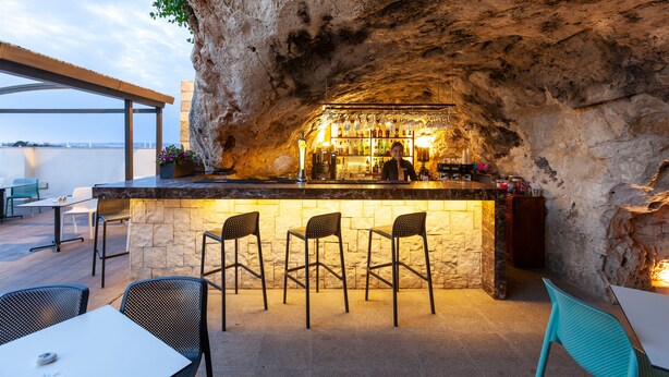 Un bar al aire libre con paredes de piedra y vistas al agua.