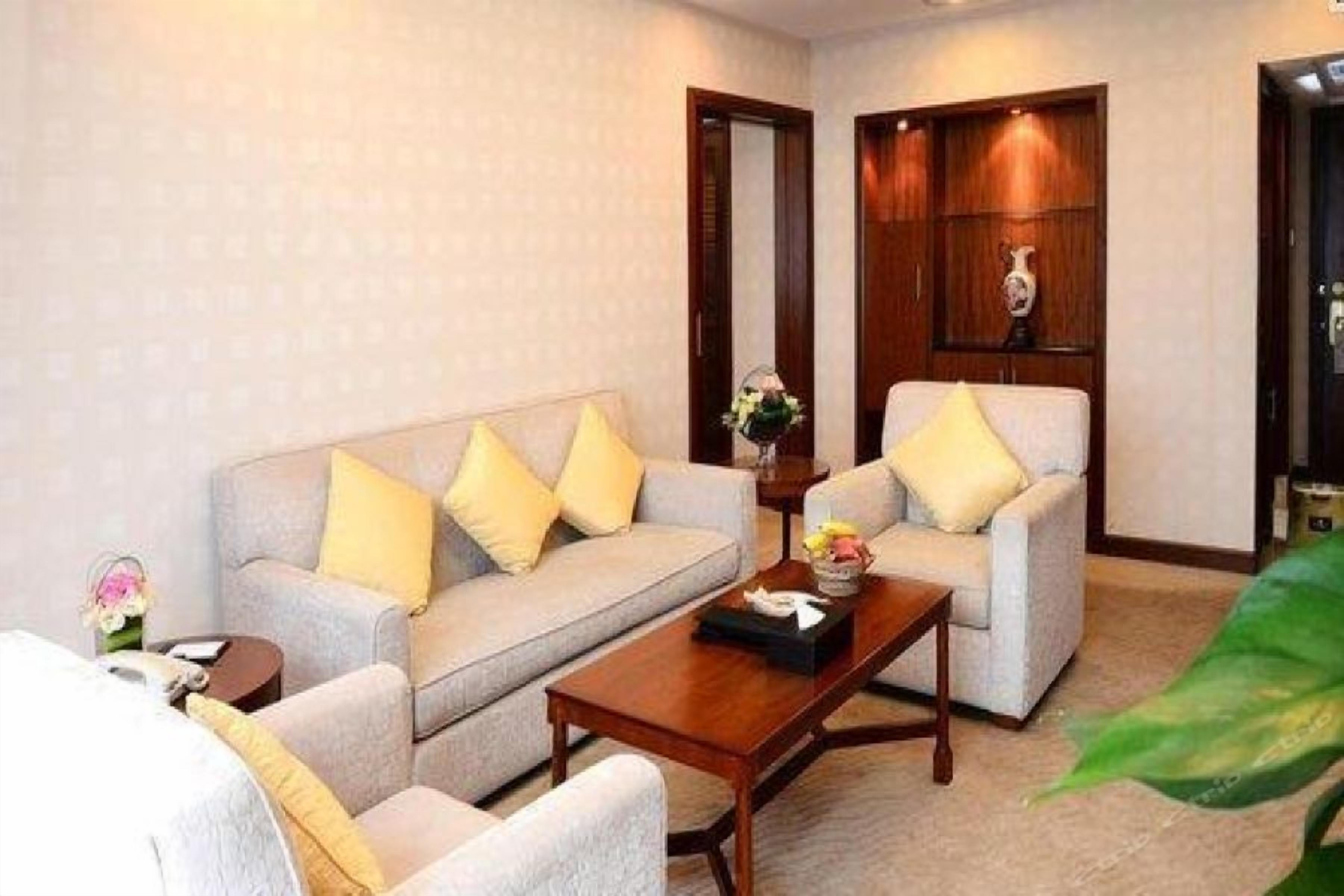 A hotel room with a sofa, armchairs, a coffee table, and a mirror.