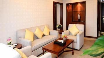 A hotel room with a sofa, armchairs, a coffee table, and a mirror.