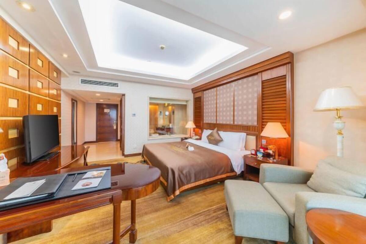 A hotel room with a skylight, a bed, a desk, a chair, and a sofa.