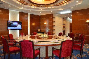 A conference room with a round table, red chairs, and a television screen mounted on the wall. - Chang an Hotel (Dongguan)