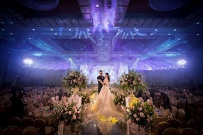 A wedding ceremony with a couple on a decorated stage, surrounded by guests. - Chang an Hotel (Dongguan)