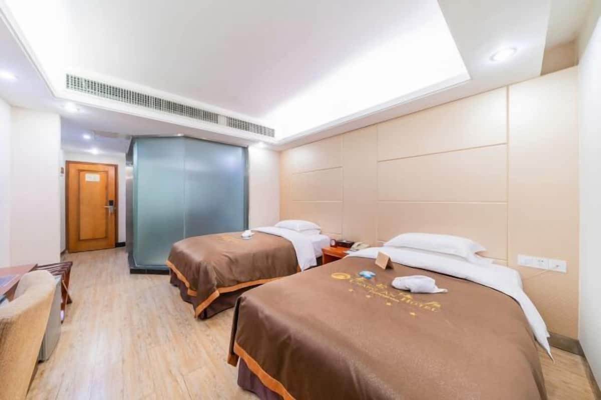 A hotel room with two beds, a desk, and a chair.