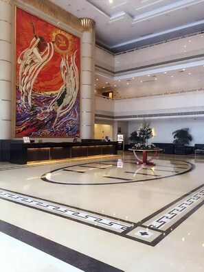 A spacious lobby with a large mural, a reception desk, and a central decorative feature. - Chang an Hotel (Dongguan)