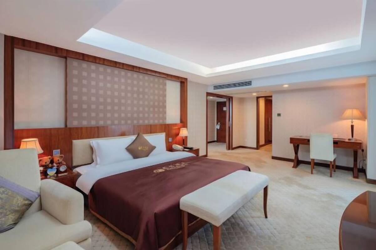 A hotel room with a large bed, bedside tables, a desk, and a chair.