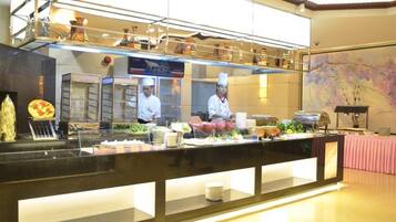 A buffet area with a variety of food items and a chef preparing food.