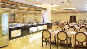 A dining area with round tables and chairs, a buffet counter, and a glass display case.