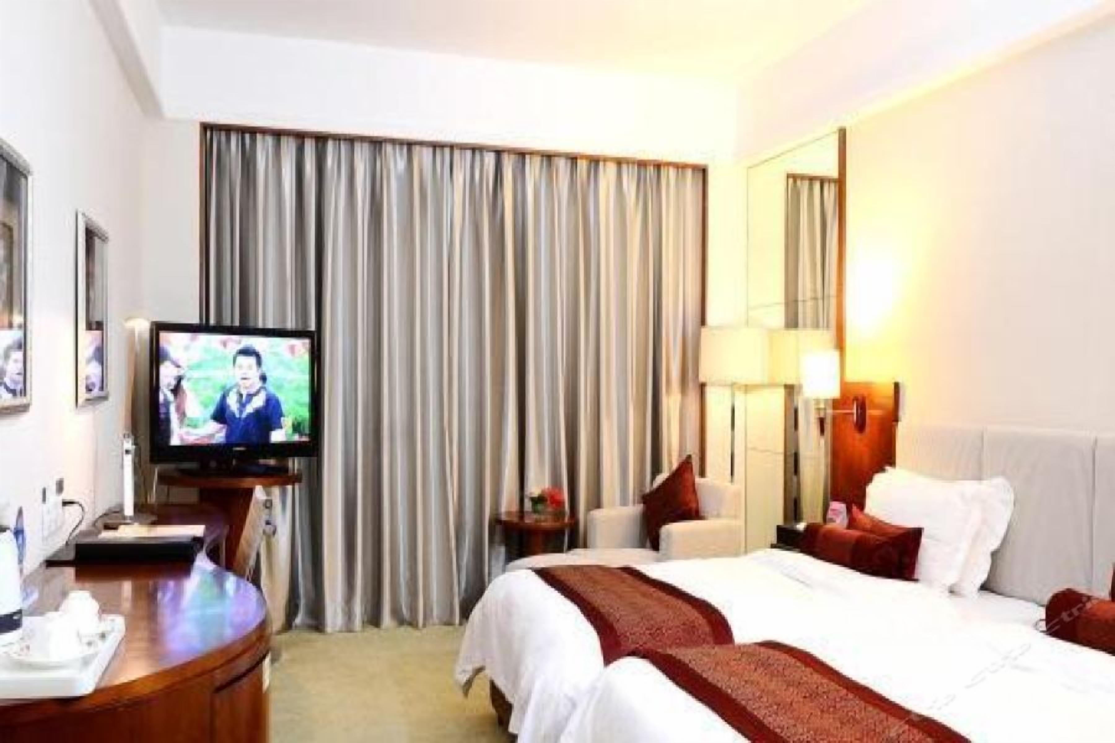 Una habitación de hotel con cama, televisión, escritorio y espejo.