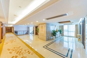 A hotel lobby with a polished floor, a reception desk, a staircase, and large windows. - Chang an Hotel (Dongguan)