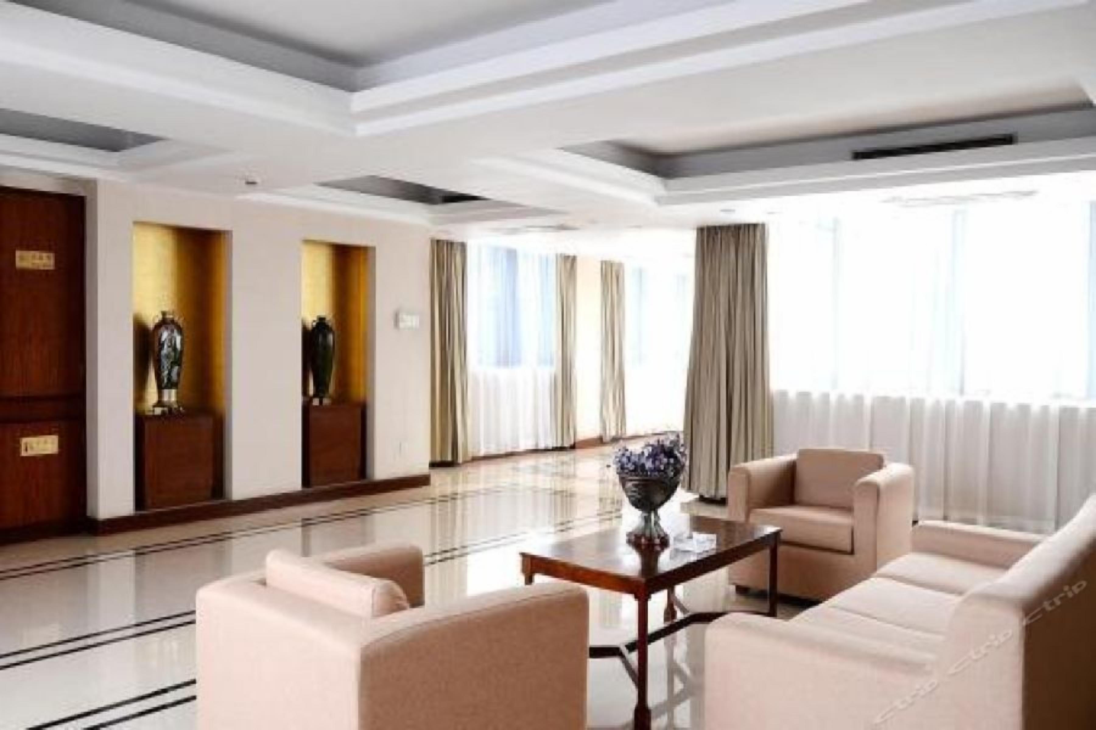 Un hall de hotel con mostrador de recepción, zona de estar y ventanas amplias.