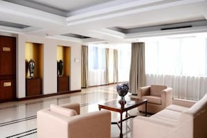 A hotel lobby with a reception desk, seating area, and large windows.