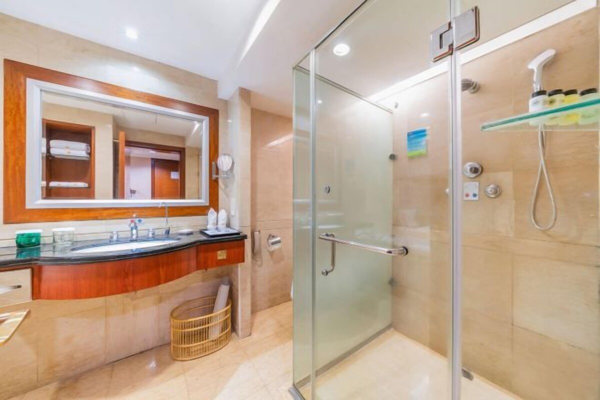 A modern bathroom with a glass-enclosed shower, a vanity with a mirror, and a towel rack.