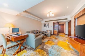 A hotel room with a sofa, a desk with a lamp, a flat-screen TV, and a patterned carpet. - Chang an Hotel (Dongguan)