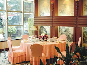 Un comedor con mesas redondas, sillas color melocotón y vistas al exterior a través de amplios ventanales.