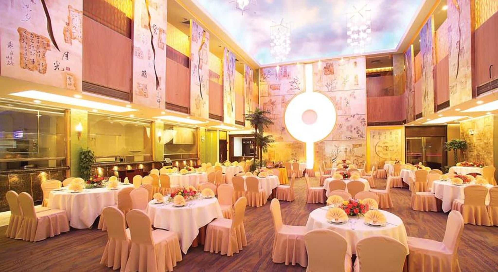 A banquet hall with round tables, chairs, and floral centerpieces.