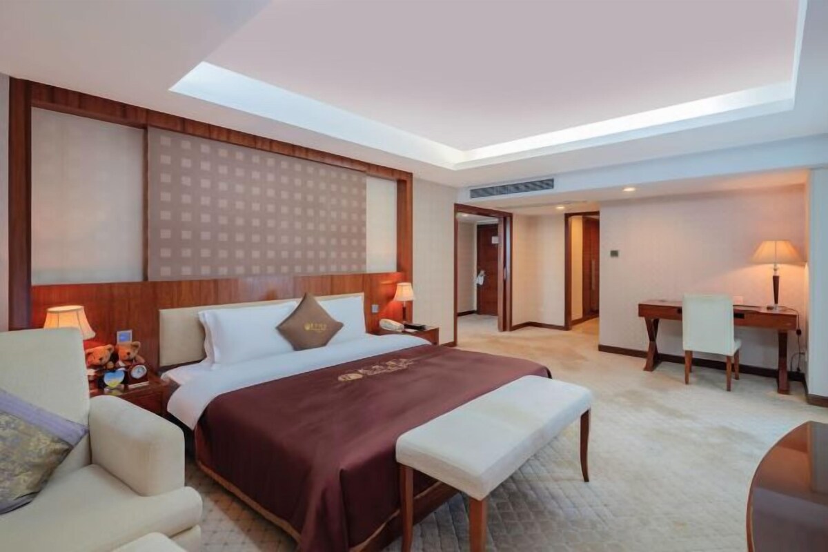 A hotel room with a large bed, bedside tables, a desk, and a chair.