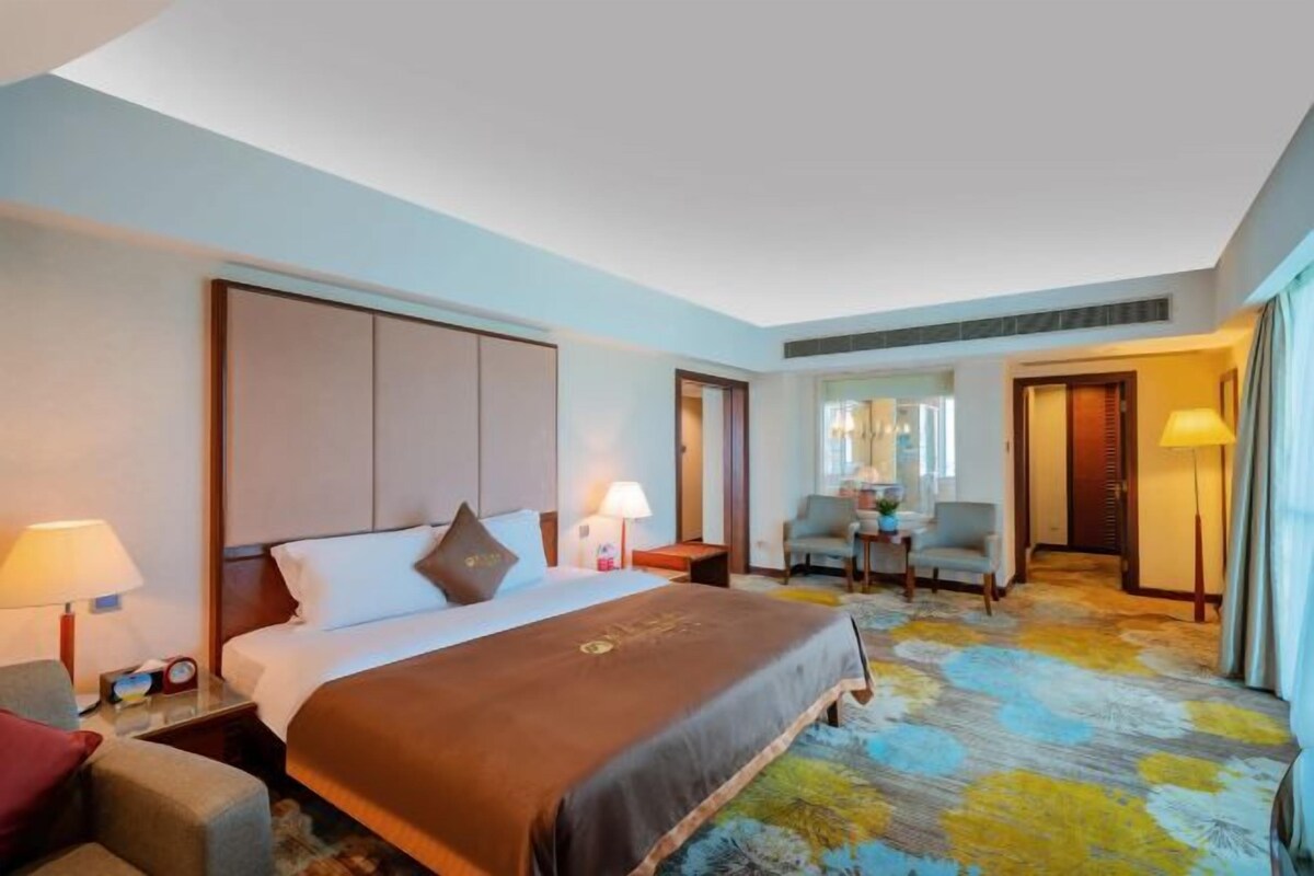 A hotel room with a bed, bedside tables, a chair, and a desk.