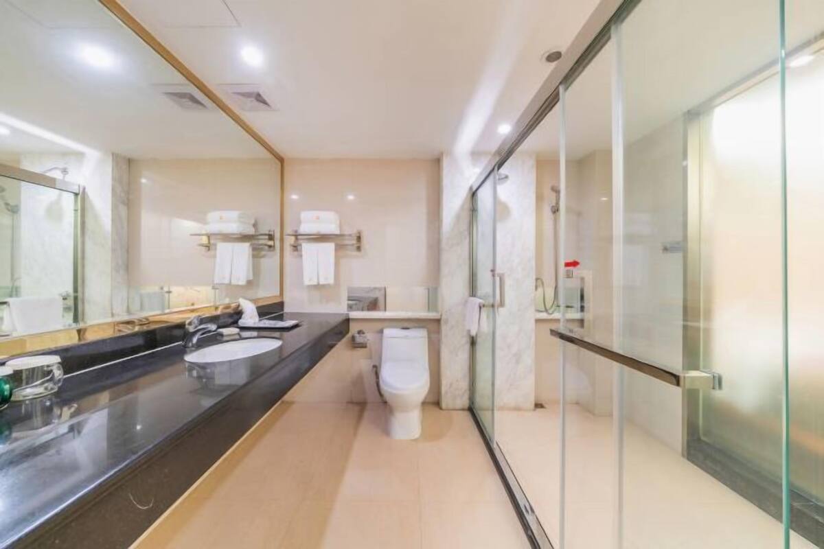 A modern bathroom with a black countertop, two sinks, a toilet, and a glass shower enclosure.