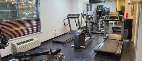 A gym with treadmills, elliptical machines, and weight equipment.