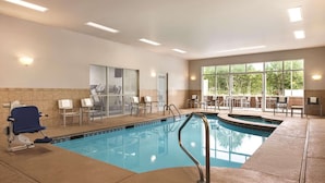 An indoor swimming pool with a blue water feature, a blue chair, and a sunlit room with a large window and a door. - Country Inn & Suites by Radisson, Conyers, GA (Conyers)