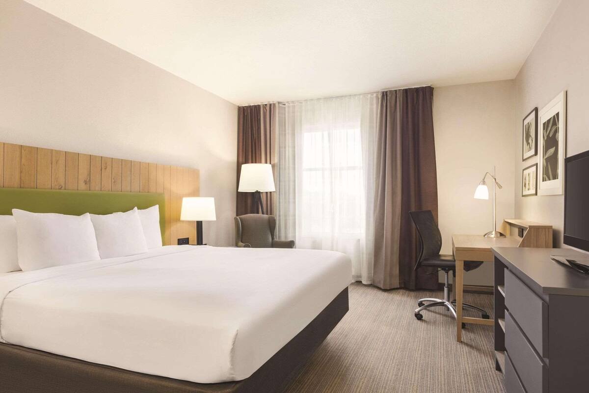 A hotel room with a large bed, a desk, a chair, and a television.