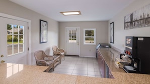 A kitchen with granite countertops, wicker chairs, a refrigerator, and a coffee machine. - Americas Best Value Inn Scarborough Portland (Scarborough)