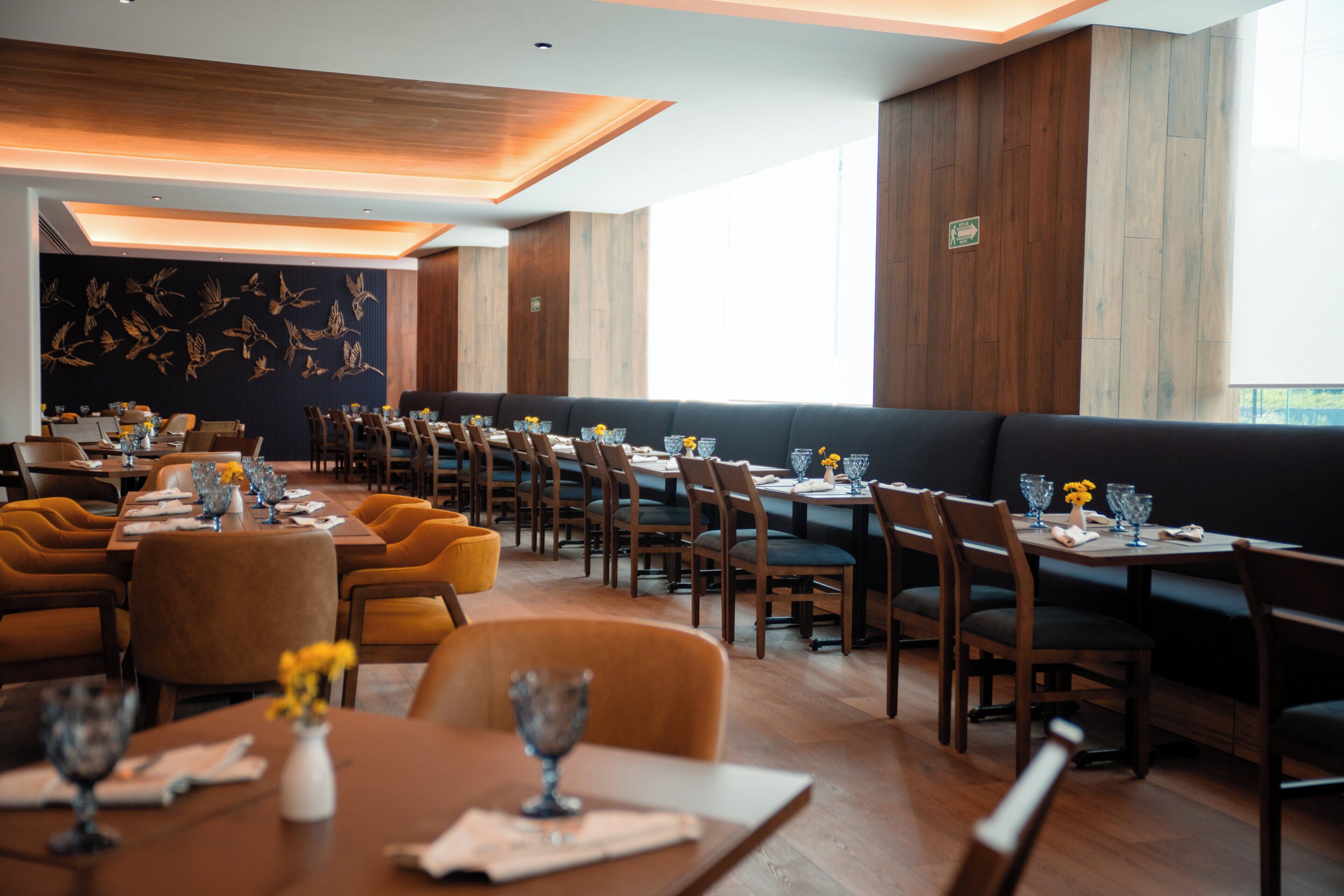 A restaurant with multiple dining tables and booths, wooden paneling on the walls, and a ceiling with recessed lighting.
