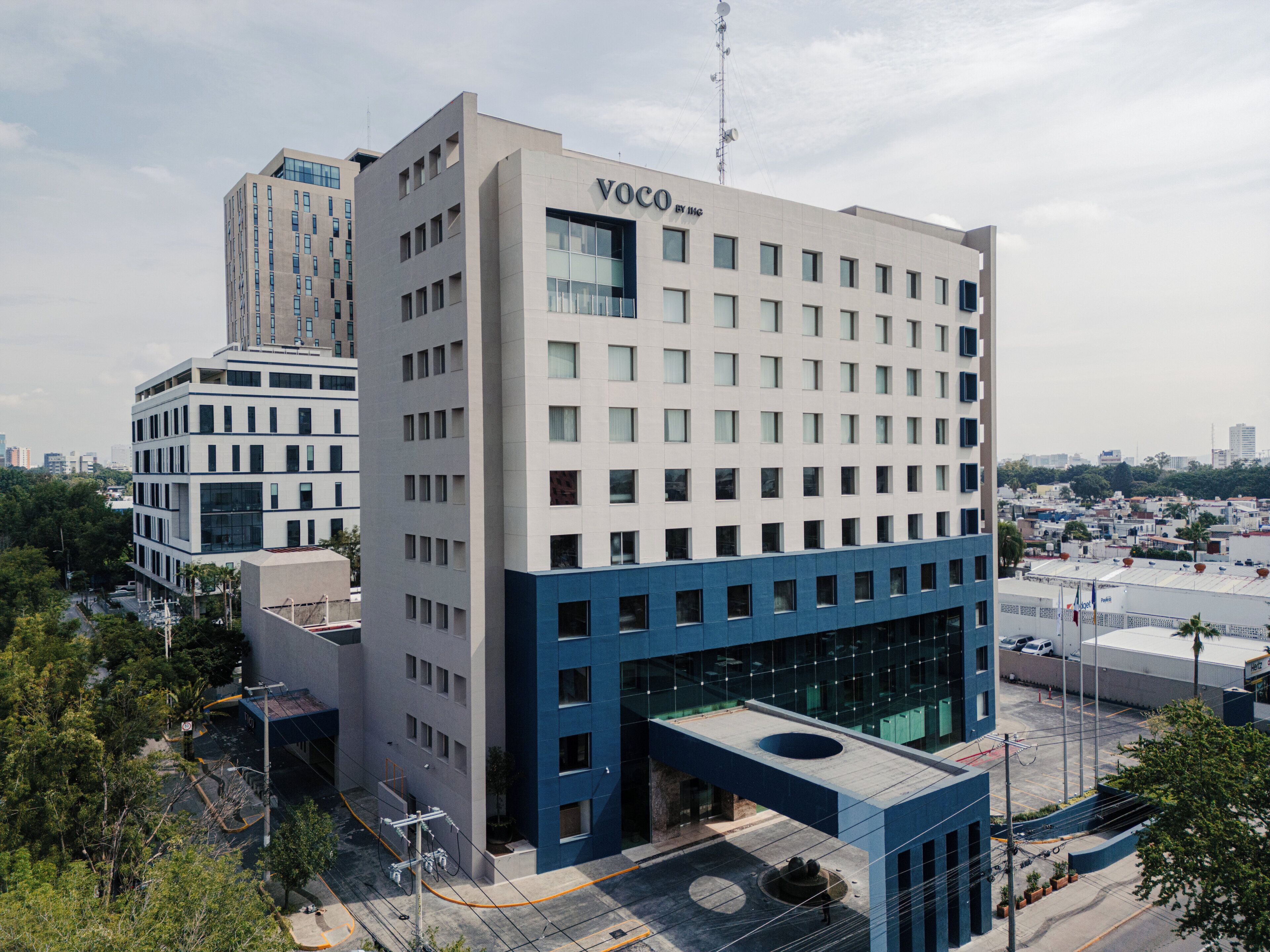 Um edifício moderno com telhado plano e uma placa com a inscrição 'VOCO BY THE'.
