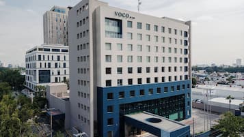 Um edifício moderno com telhado plano e uma placa com a inscrição 'VOCO BY THE'.