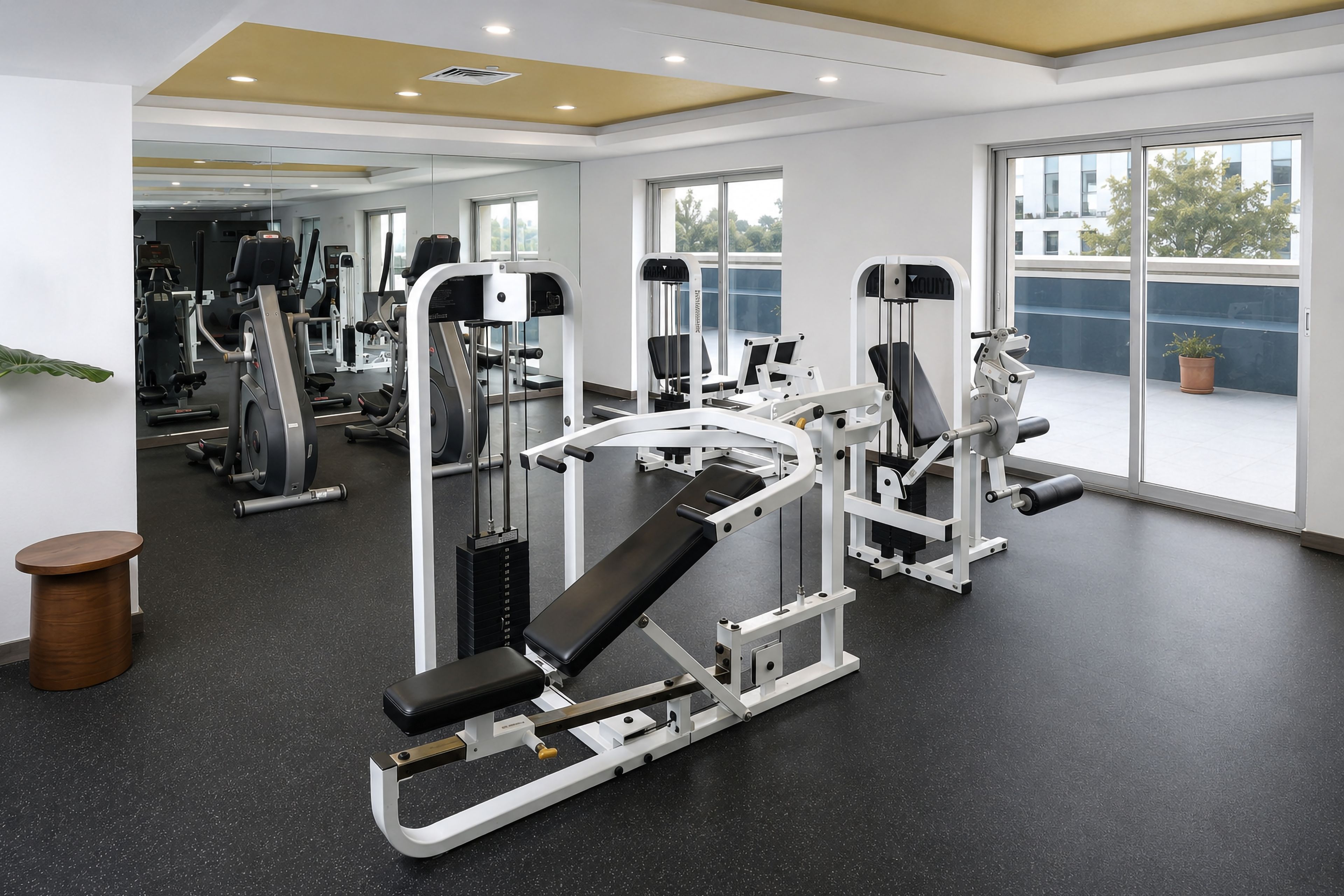 Ein Fitnessstudio mit verschiedenen Trainingsgeräten, großen Fenstern und einem klaren, modernen Design.