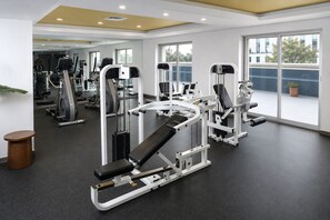 Une salle de sport équipée de divers appareils d’exercice, dotée de grandes fenêtres et présentant un design moderne et épuré.
