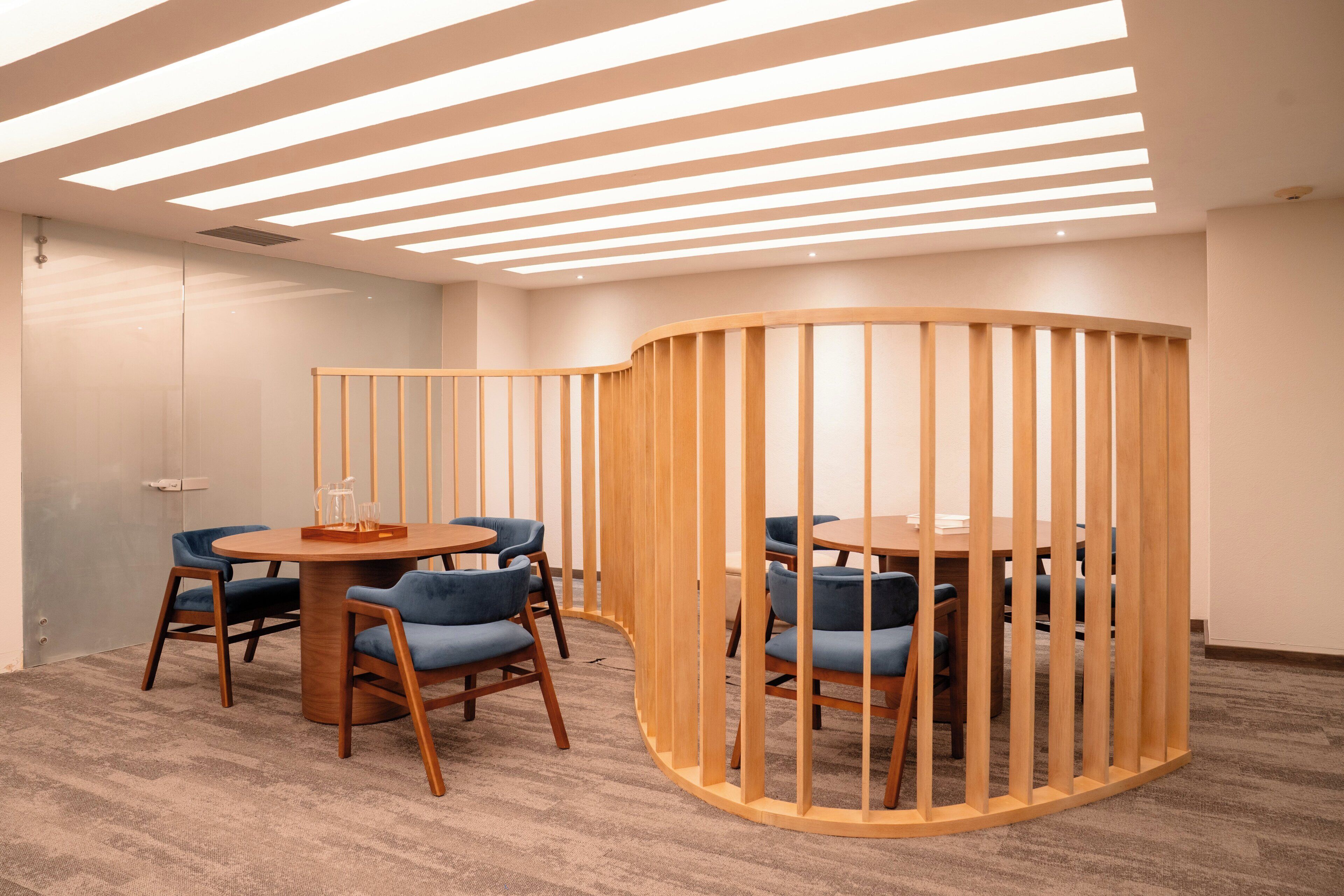 A conference room with a wooden partition, round tables, and blue chairs.