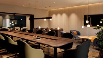 Uma sala de conferências moderna com uma mesa comprida, várias cadeiras e uma tela de televisão.