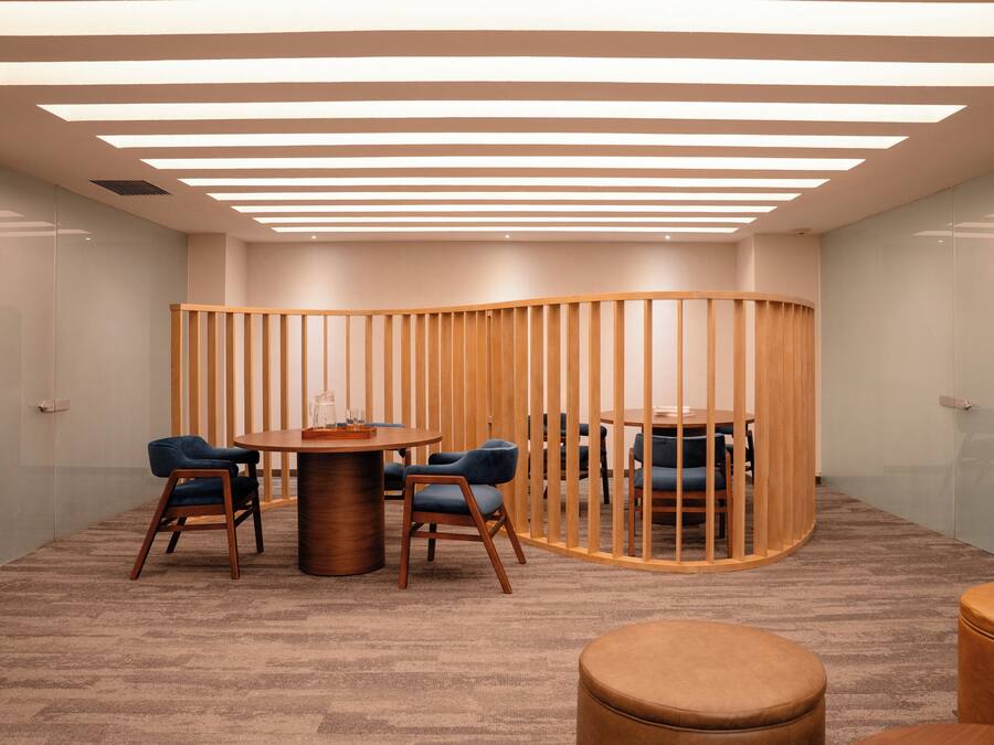 A conference room with a round table, six chairs, a wooden partition, and a carpeted floor.