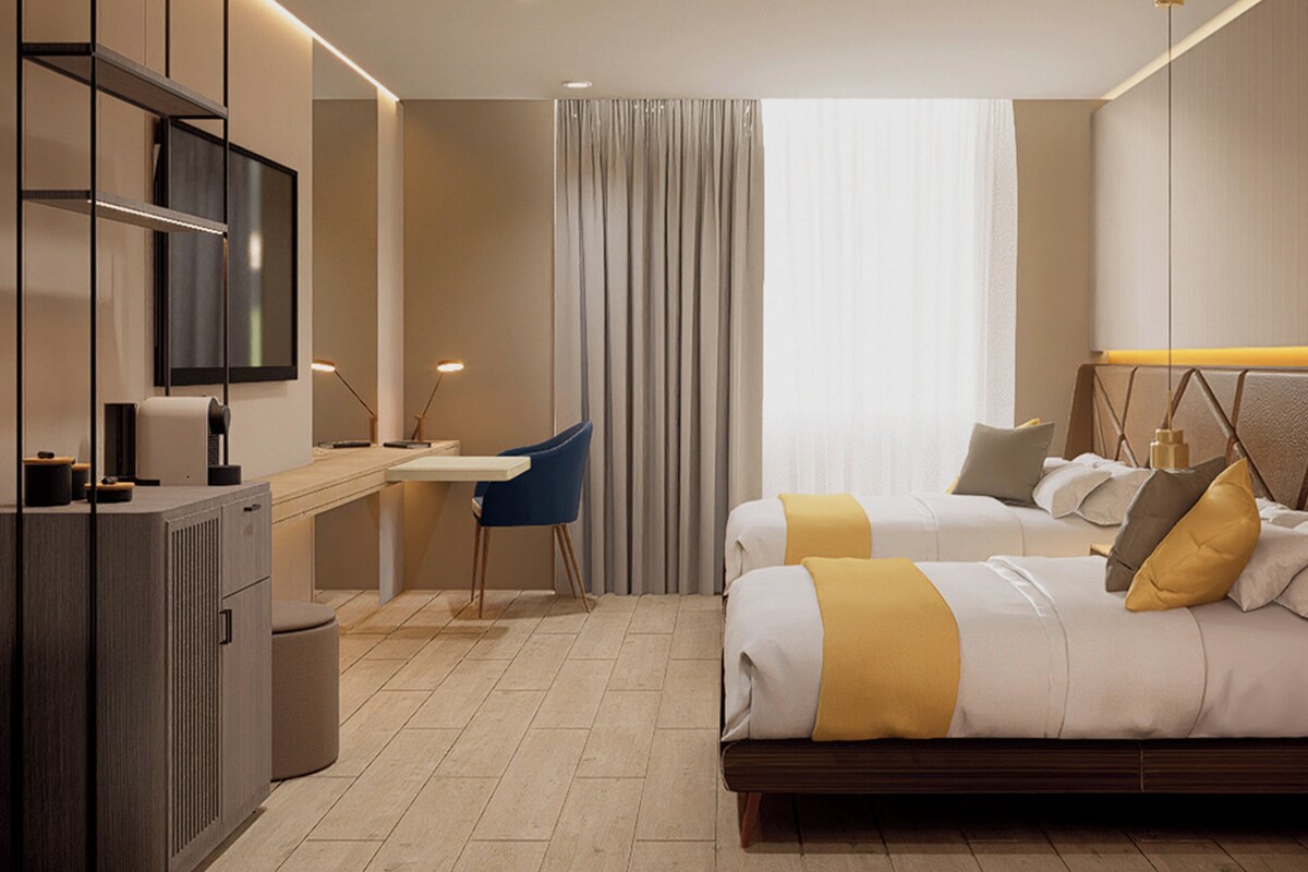 A hotel room with a bed, a desk, a chair, and a television.
